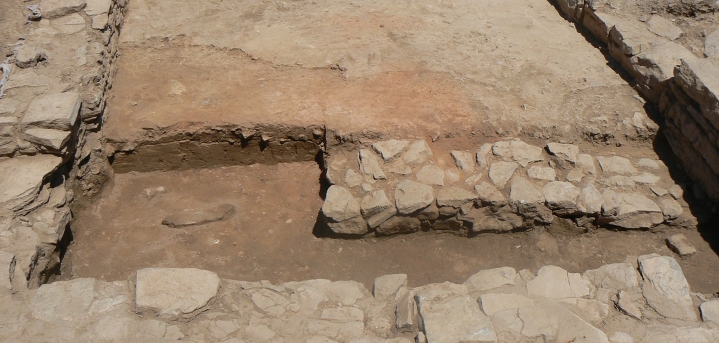 The process of excavating the hearth (redder area). At the bottom of the picture can be seen the test trench thanks to which the wall from the intermediate phase was discovered